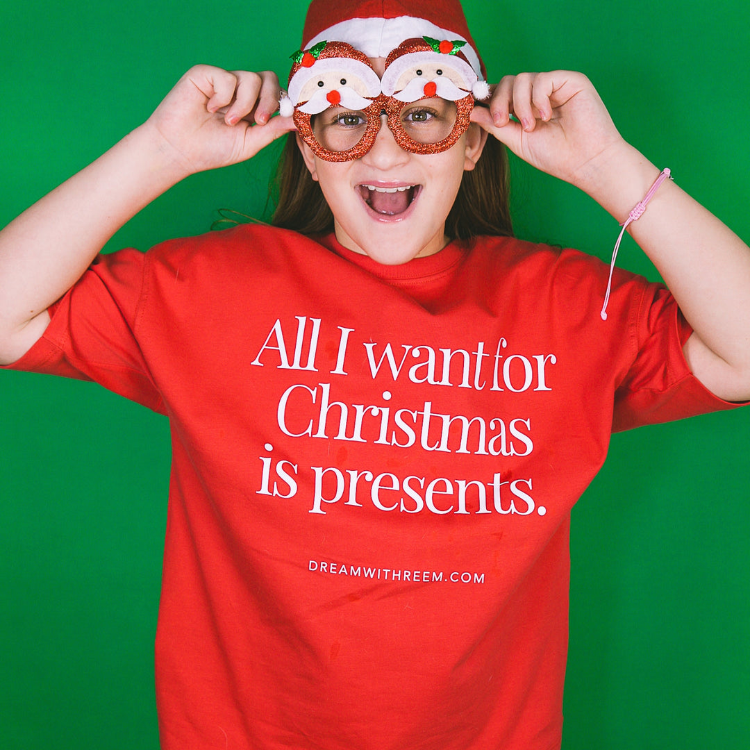 Child smiling in red All I Want For Christmas T-Shirt with fun holiday accessories