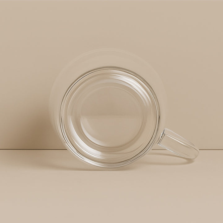 Transparent customizable glass coffee cup with handle shown from top view on beige background