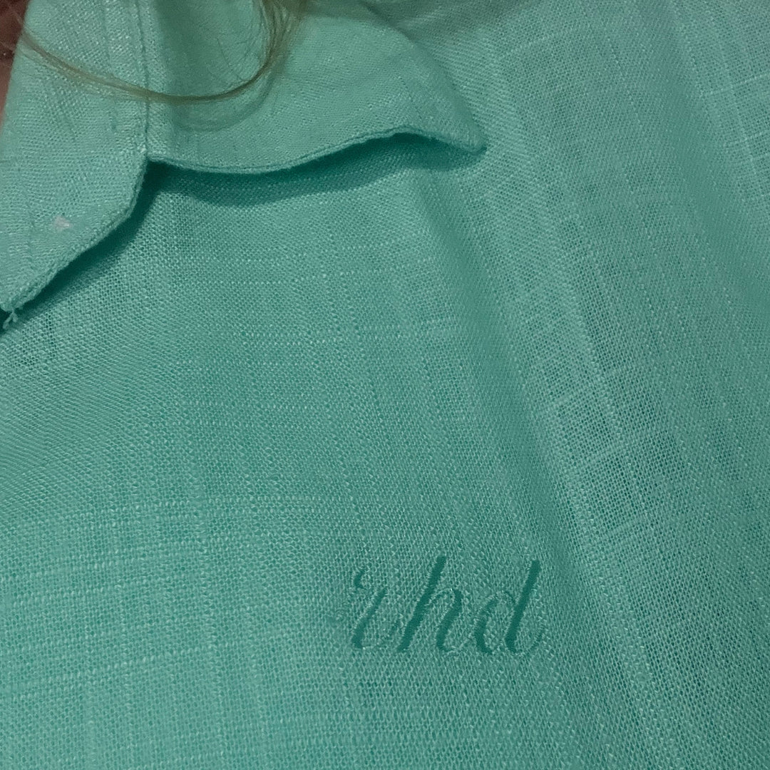 Close-up of custom embroidery showcasing initials on a light green fabric by dreamwithreem, featuring custom embroidery service Dubai