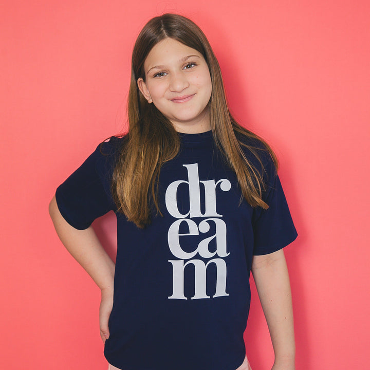 Girl wearing navy blue custom icon tee with white vertical dream text on front