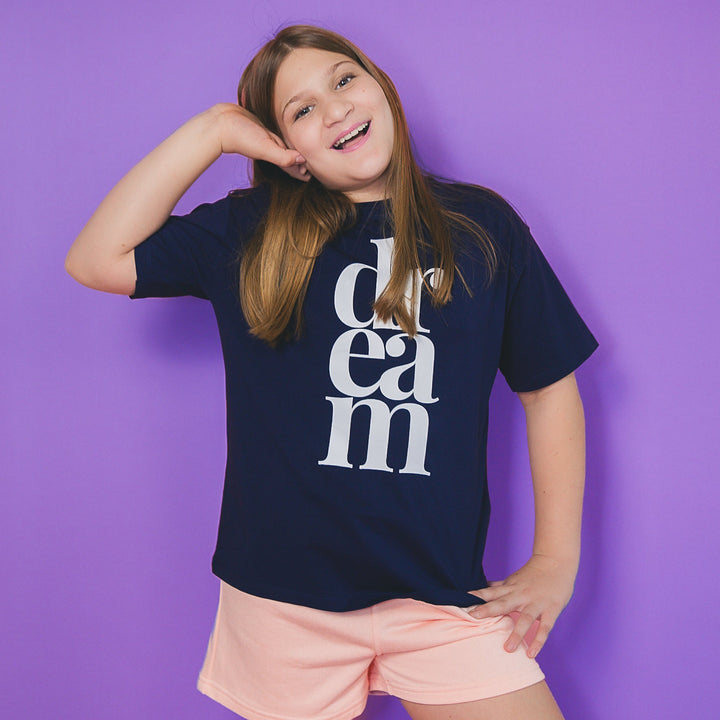 Girl wearing a navy blue custom icon tee with white dream text against a purple background