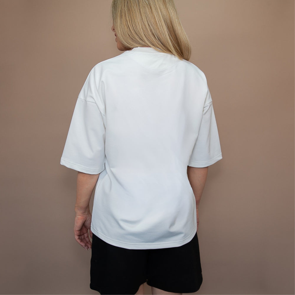 Back view of a woman wearing a white custom oversized tee paired with black shorts