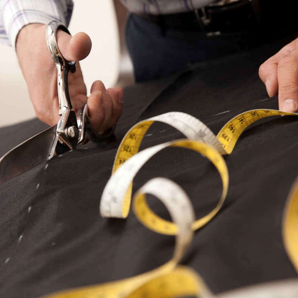 Experienced tailor providing custom tailoring service Dubai with scissors and measuring tape on fabric