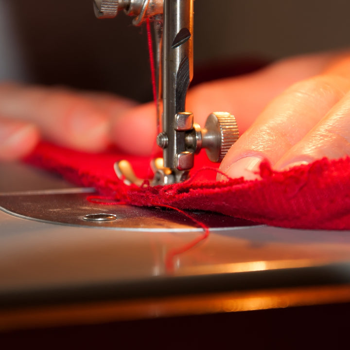 Close-up of hands operating a sewing machine showcasing custom tailoring service Dubai