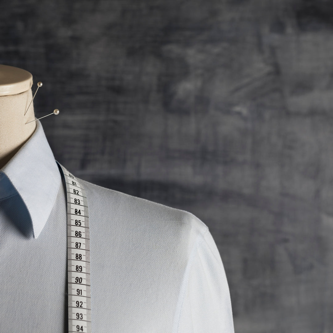 Custom tailoring service Dubai with measuring tape on a light blue shirt for personalized fits
