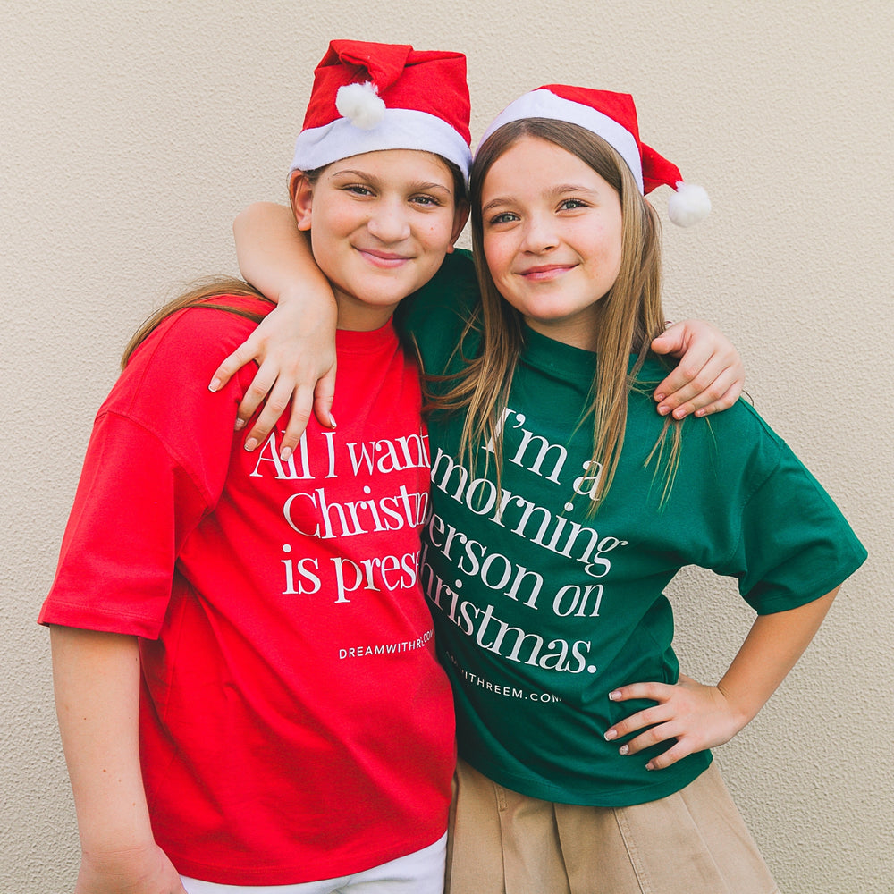 Custom Christmas morning t-shirt in red and green worn by kids with Santa hats for festive celebrations