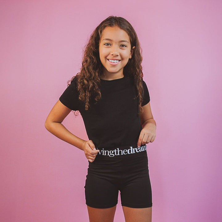 Young girl wearing black activewear set with everyday wearable shorts by dreamwithreem on pink background