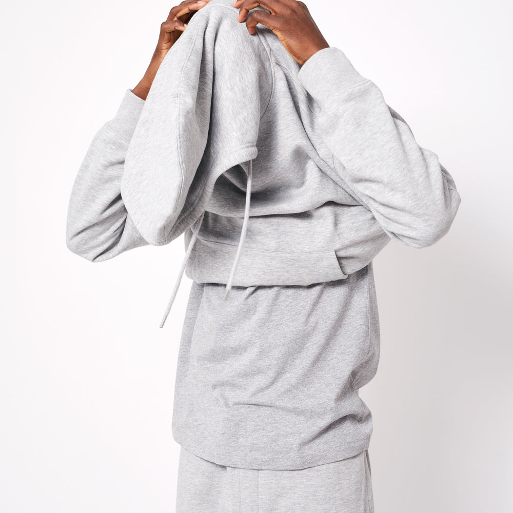 Man putting on a gray personalized hoodie online with adjustable hood and comfortable fit