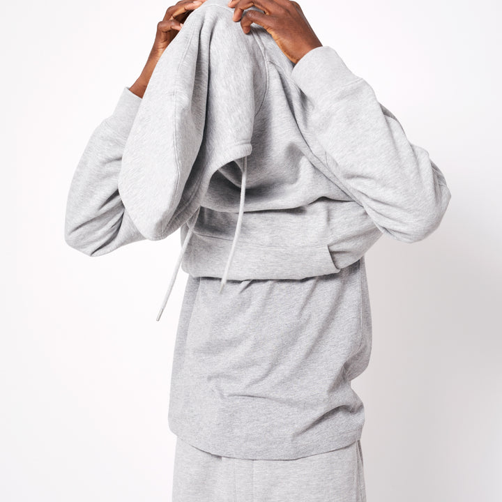 Man putting on a gray personalized hoodie online with adjustable hood and comfortable fit