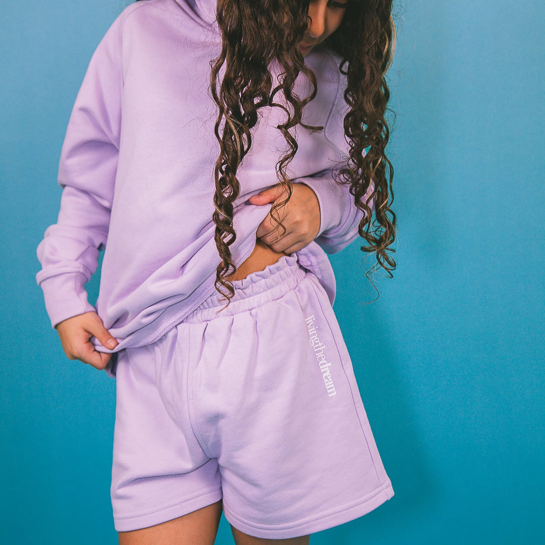 Child wearing a personalized purple hoodie outfit with matching shorts against blue background