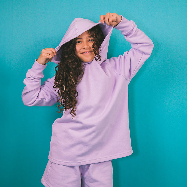Young girl wearing a personalized purple hoodie outfit with matching shorts against blue background