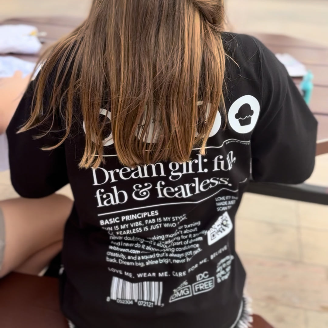 Woman wearing a black custom statement t-shirt by dreamwithreem with white text and graphics on the back